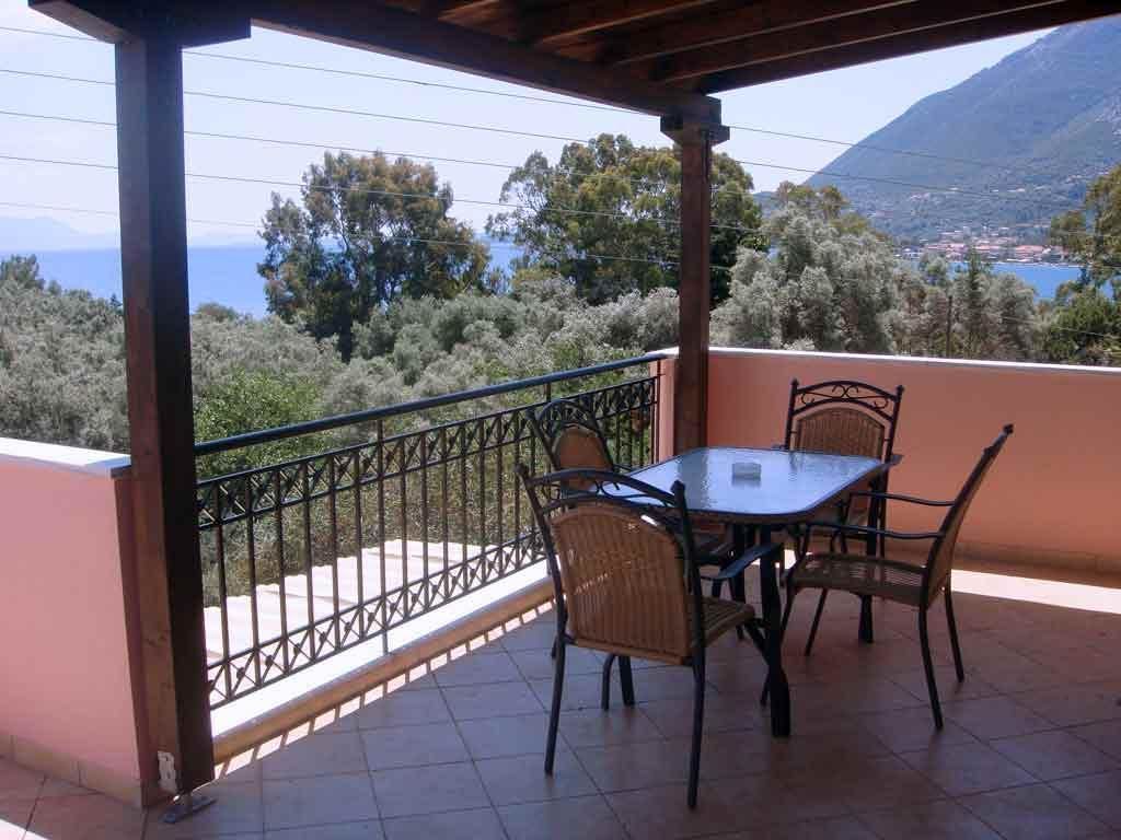 Un espace extérieur abrité, doté d’une table et de chaises, d’une rambarde en métal et offrant une vue sur un paysage montagneux.
