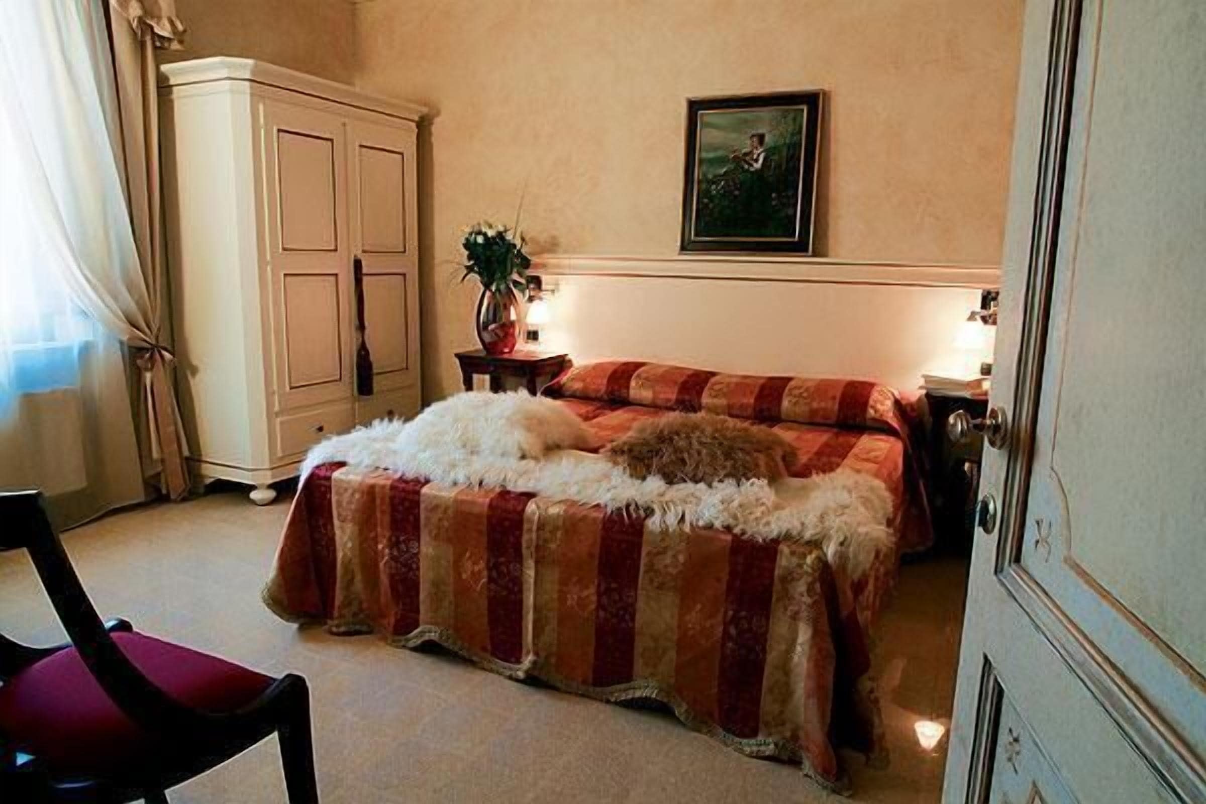 Une chambre à coucher avec un lit, une armoire, une chaise et un tableau au mur.