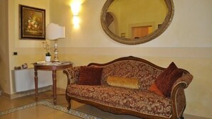 A room with a patterned sofa, a round mirror, a lamp, and a framed picture on the wall. - Villa della Certosa (Gambassi Terme)
