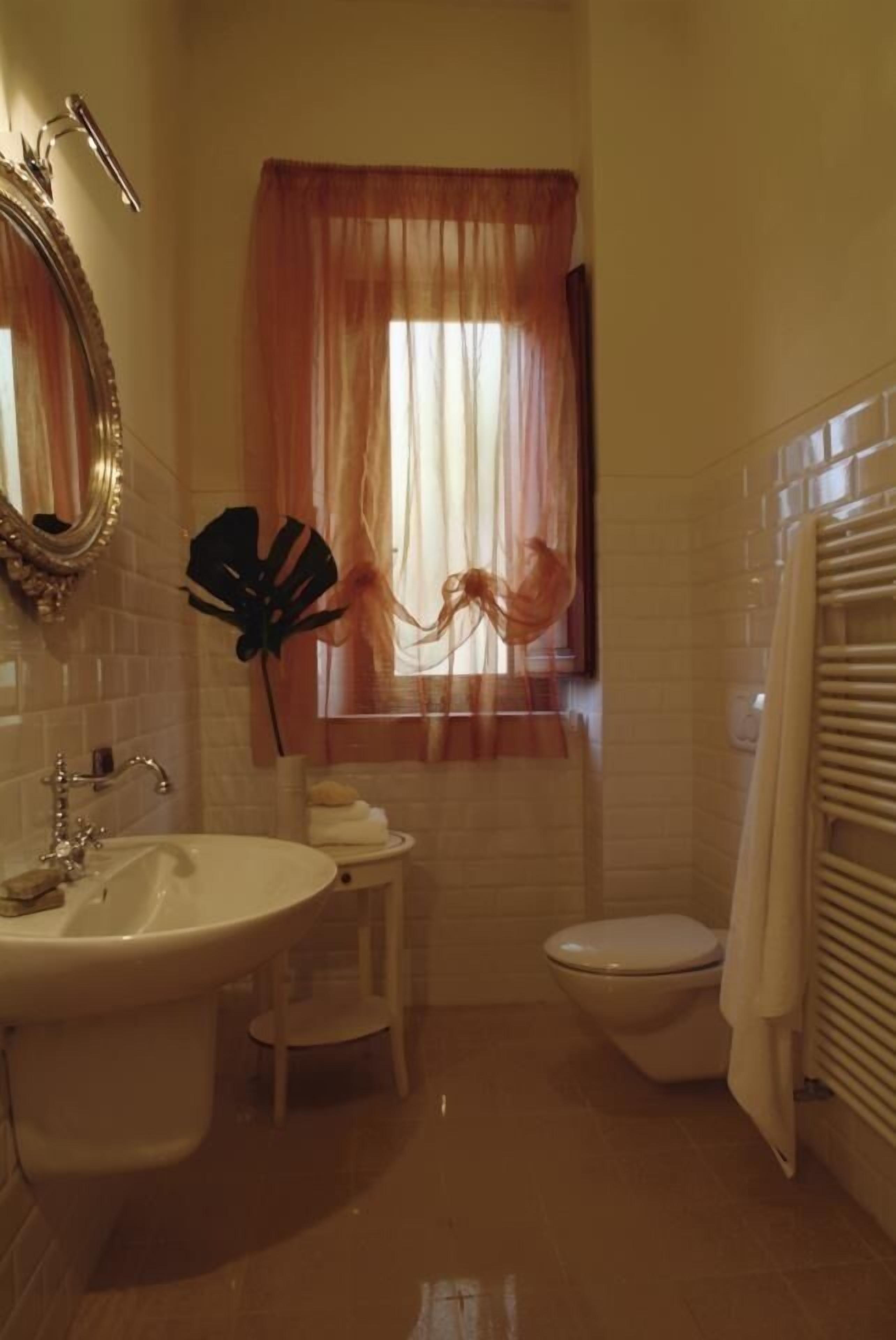 A bathroom with a sink, toilet, and a window with curtains.
