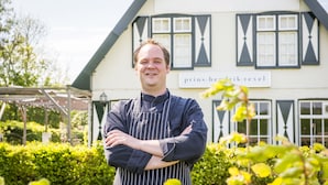 Una persona de pie frente a un edificio con un letrero que dice "prins. hendrik.texel".
