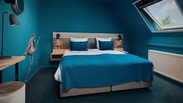 Un dormitorio con una cama grande, dos mesitas de noche, una lámpara, un reloj en la pared y un tragaluz.