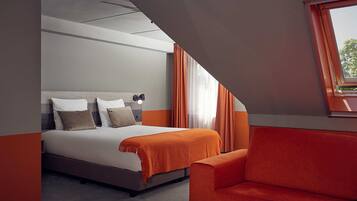 A modern hotel room with a bed, a sofa, and a window with curtains.