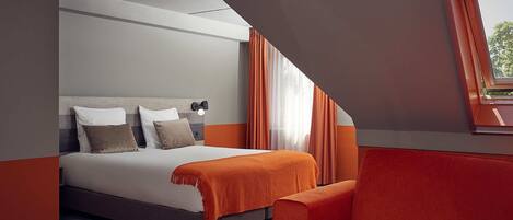 A modern hotel room with a bed, a sofa, and a window with curtains.