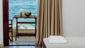 Habitació d'hotel amb un llit, una taula amb articles per esmorzar, vista al mar i una cortina.