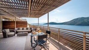 A terrace with a wooden pergola, outdoor seating, and a table set with fruits and drinks. - San Nicolas Resort Hotel (Lefkada)