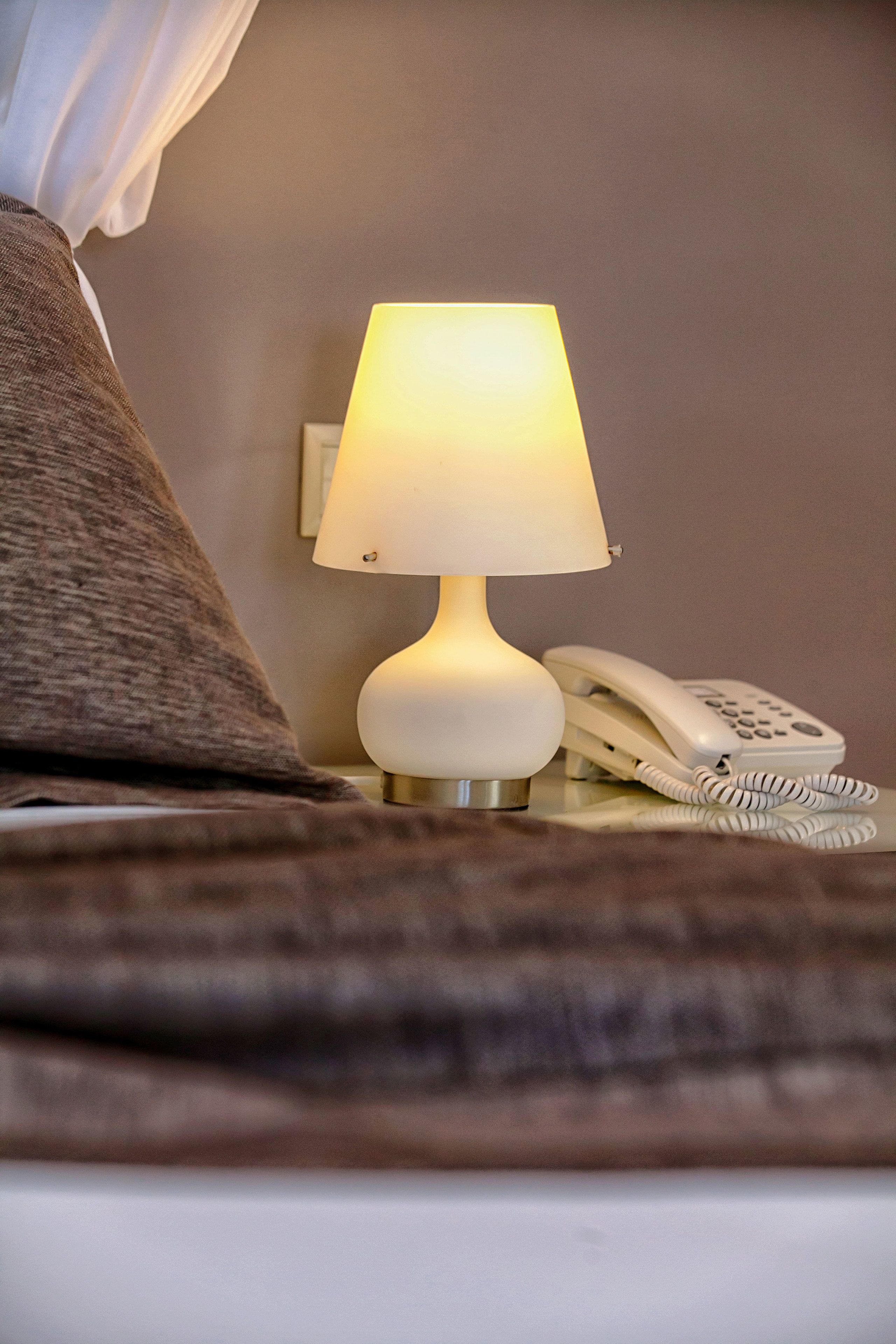 Een bedlampje en een telefoon op een nachtkastje.