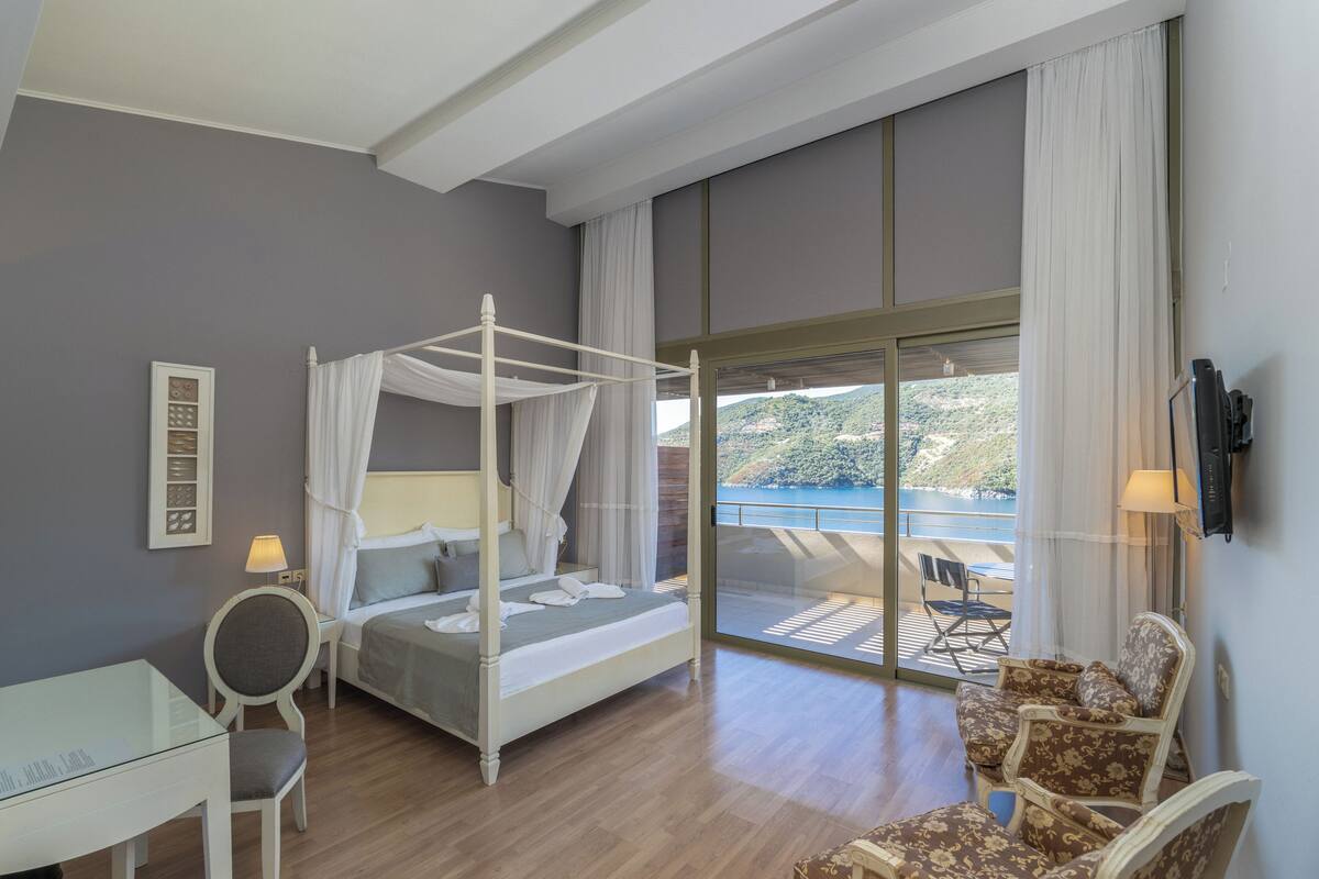 Un dormitorio con cama con dosel, un escritorio, una silla y vistas al exterior.