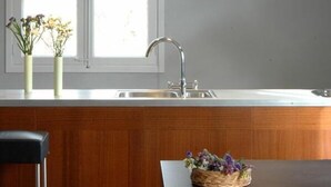 A kitchen with a wooden countertop, a sink, and hanging pendant lights. There are two vases with flowers on the countertop. - loftOtel canet (Esporles)