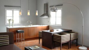 A modern kitchen with a central island, pendant lights, and a tall floor lamp. - loftOtel canet (Esporles)