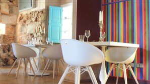 A dining area with a stone wall, a teal door, and a colorful striped wall. - loftOtel canet (Esporles)