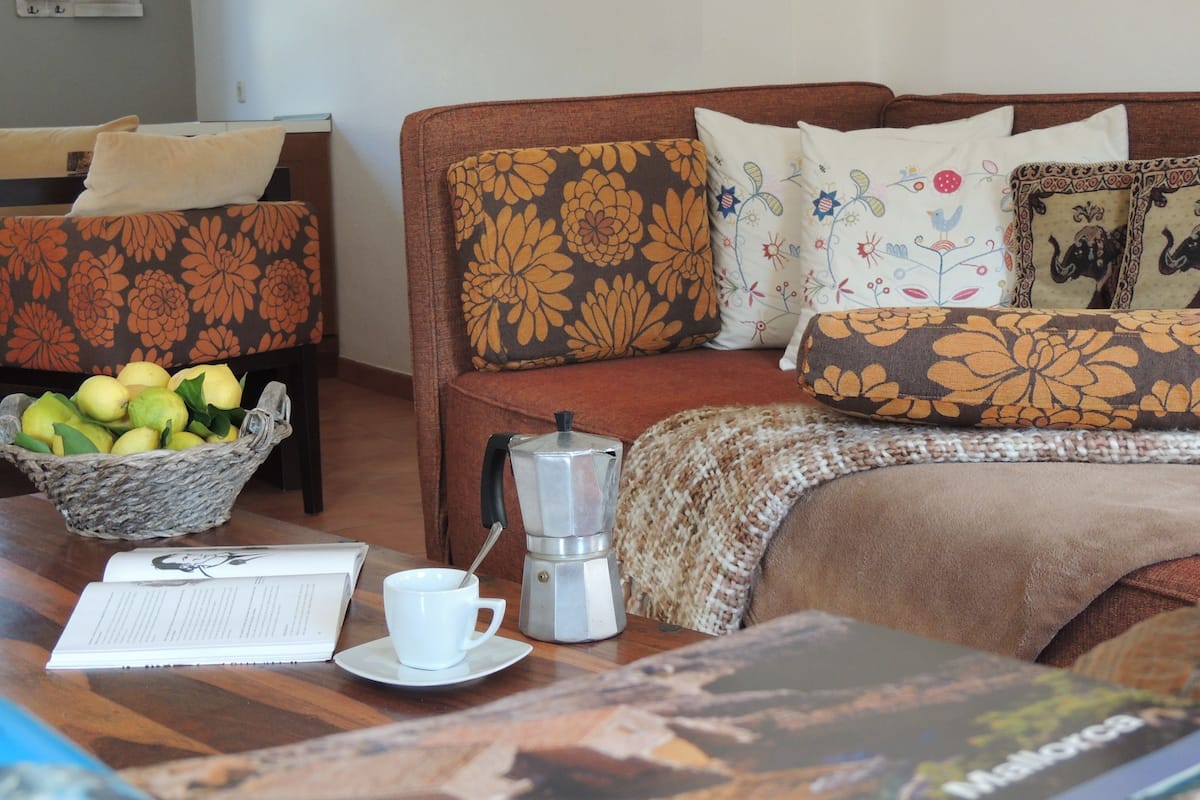 Una habitación de hotel acogedora con una cama, una mesa de centro con un cesto de limones, una cafetera y un libro.