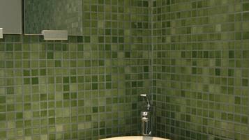 Um banheiro com pia branca, espelho e azulejos de mosaico verde.