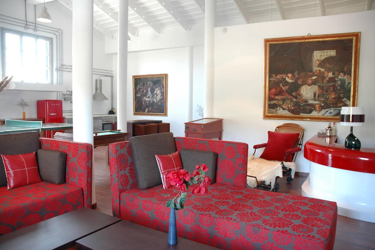 Amplia sala de estar con un juego de sofá rojo, mesa de billar y un cuadro grande en la pared.