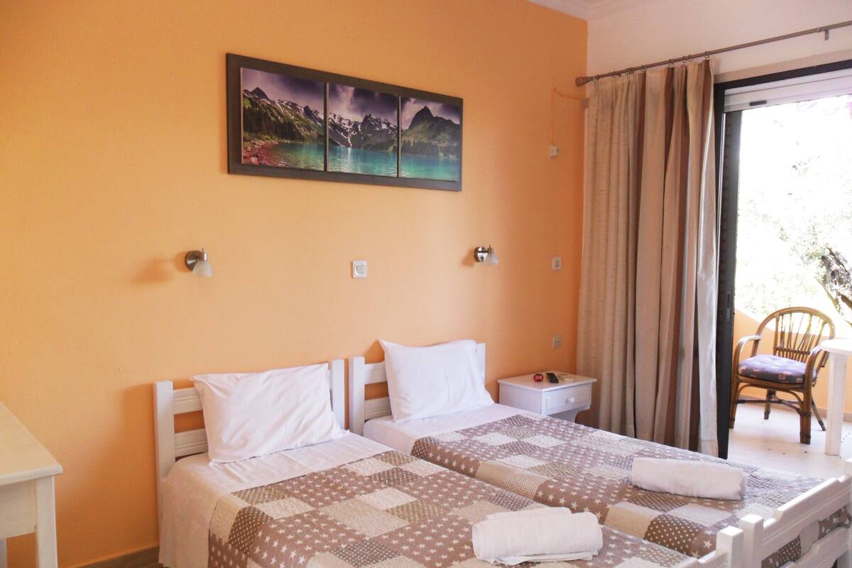 A hotel room with a bed, a nightstand, a chair, and a painting on the wall.
