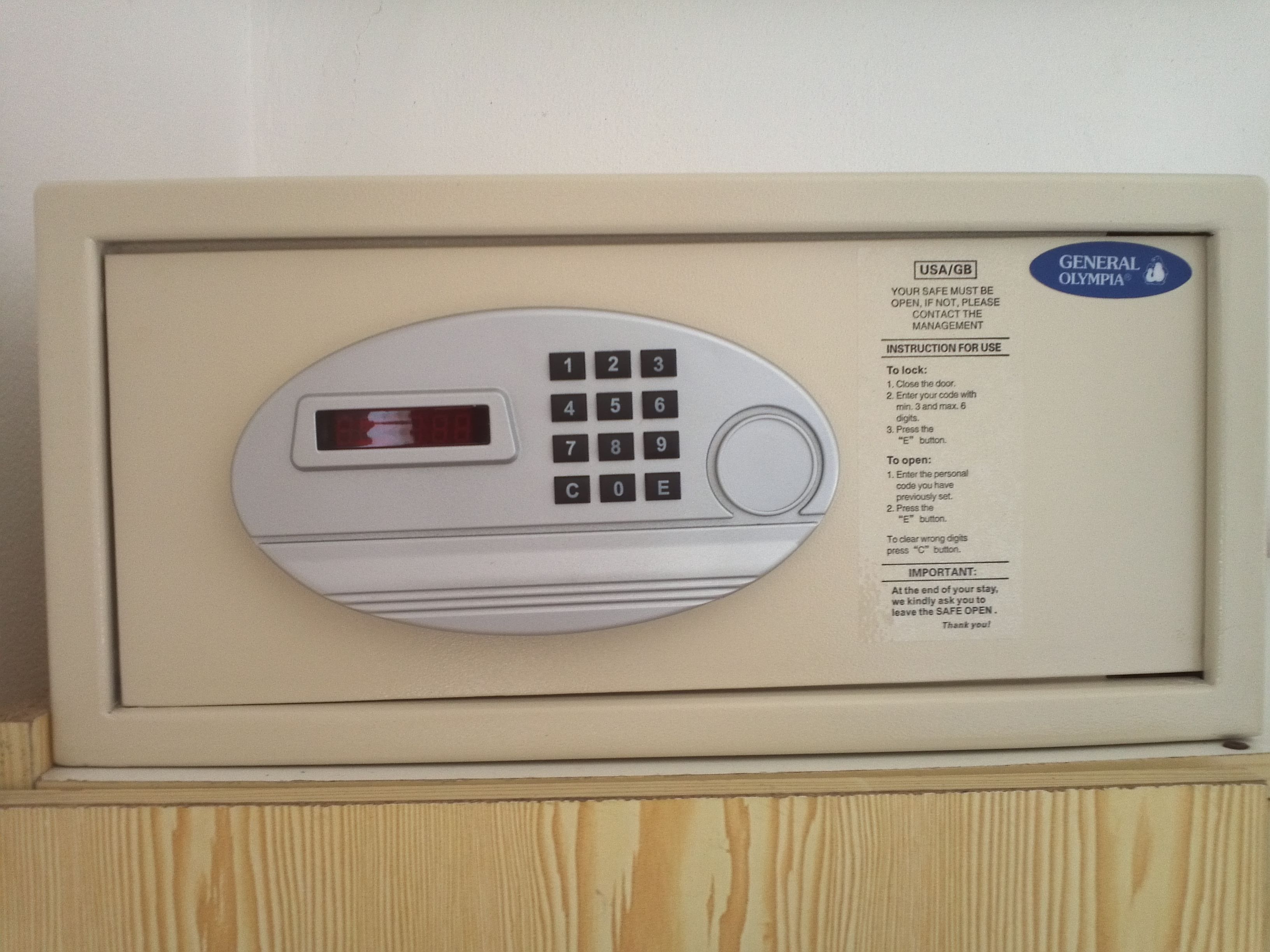 Een General Olympia kluis met numeriek keypad en een klein display, geplaatst in een beige frame.