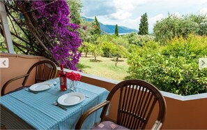 A table set for two with a view of a garden and mountains. - Marilena Apartments & Studios (Corfu)