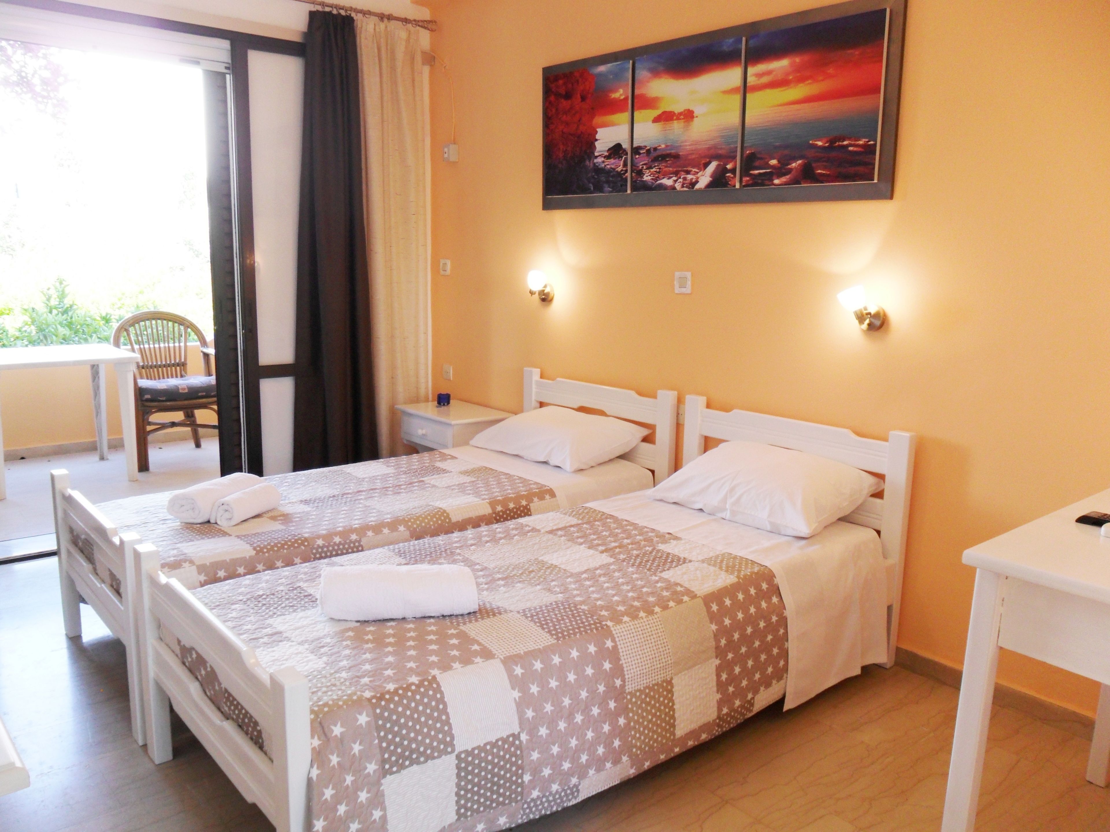 A double bed with a quilt, two bedside tables, a chair, and a painting on the wall.