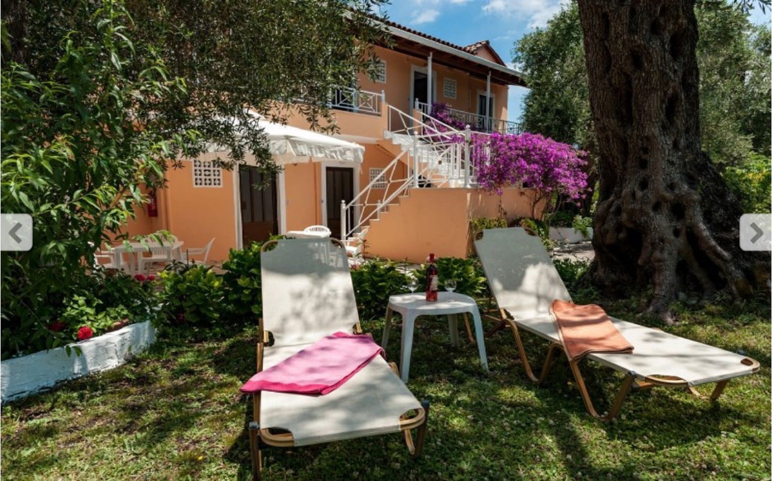 A villa with a terrace, two lounge chairs, a table, and a bottle of wine.