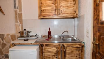 A compact kitchen with wooden cabinets, a white refrigerator, a stove, and a sink.