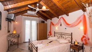 A bedroom with a wooden ceiling, a bed with white linens, a bedside table with a lamp, and a wall-mounted air conditioner. - Lofos Studios (Zakynthos)