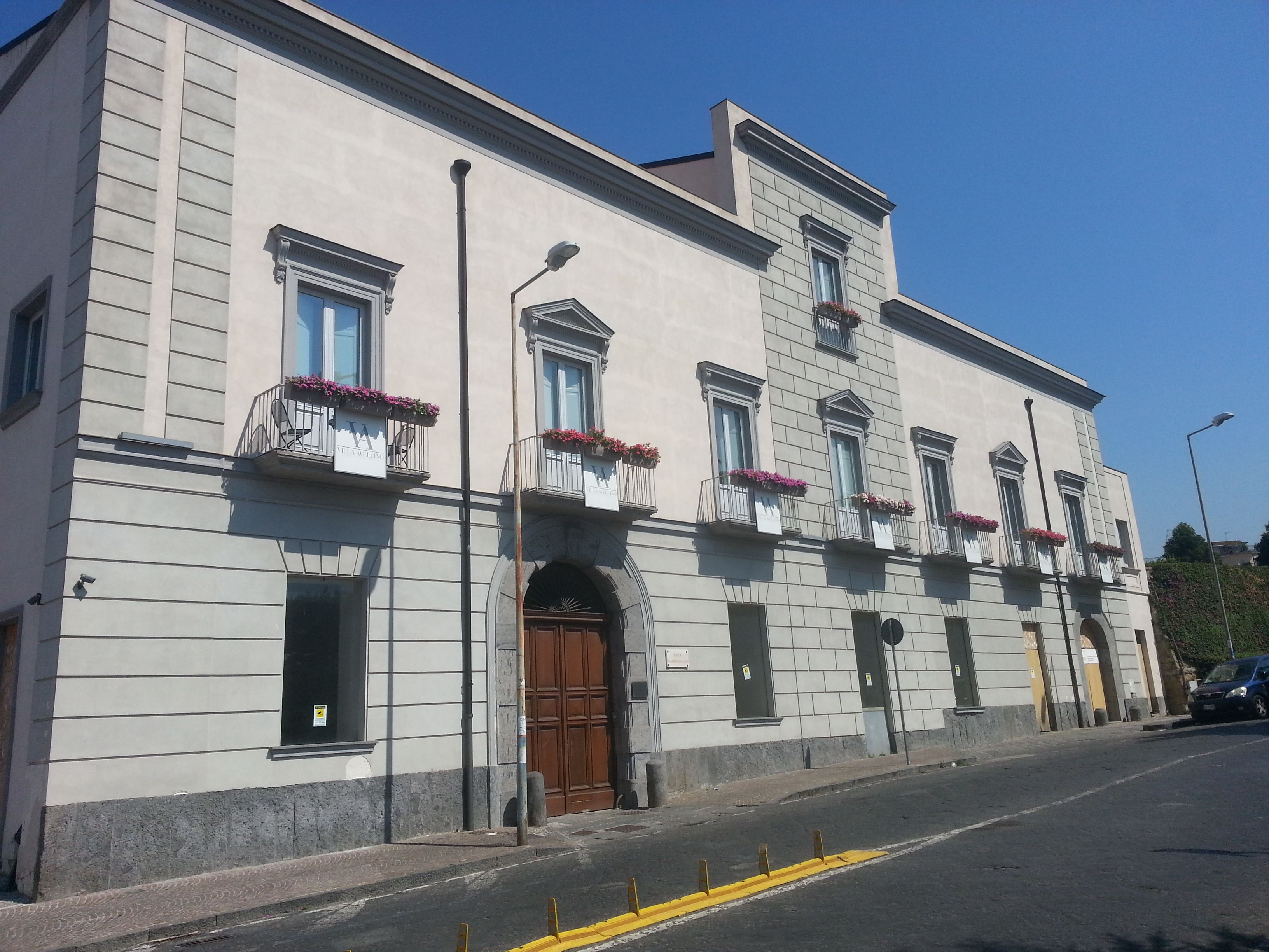 A building with a classic architectural style, featuring a symmetrical facade with evenly spaced windows and balconies adorned with flower boxes.