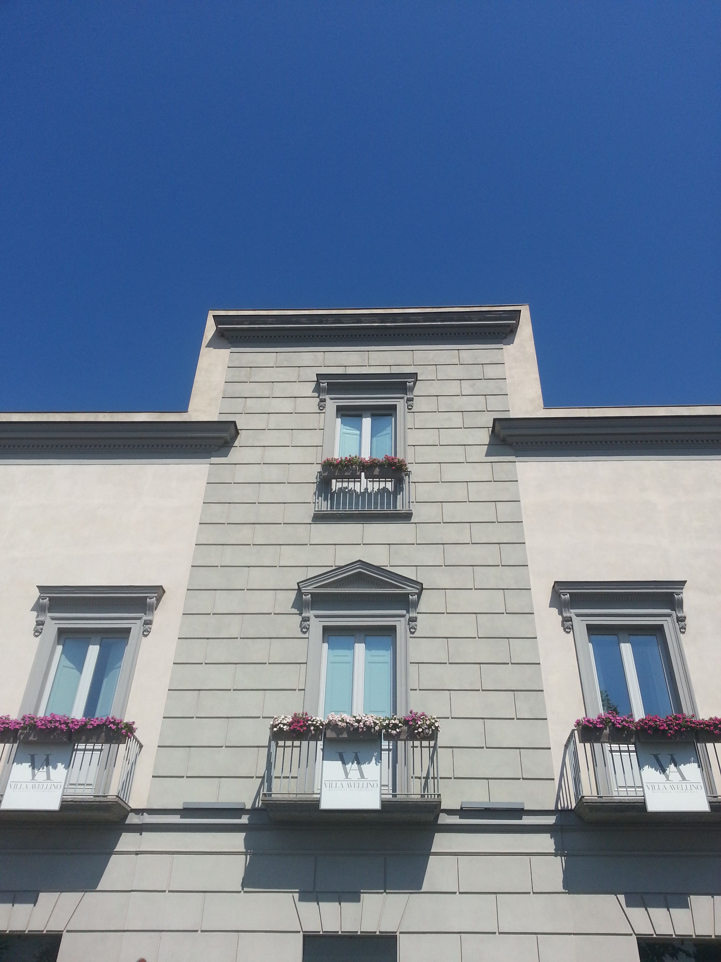 A building with a symmetrical facade, three windows on the ground floor, and two balconies with flower boxes.