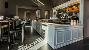 A modern kitchen with a central island, stainless steel appliances, and a seating area with chairs and tables. - Villa Avellino (Pozzuoli)