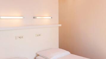 Habitación de hotel con dos camas, un techo a rayas naranjas y luces fijadas a la pared.