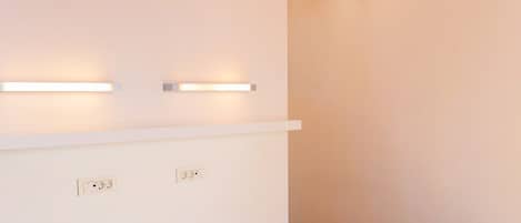 Une chambre d’hôtel avec deux lits, un plafond à rayures orange et des lampes fixées au mur.