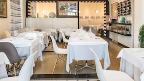 Ein Restaurant mit weißen Tischen und Stühlen, einer Bar und einem Weinkühlschrank an der Wand.