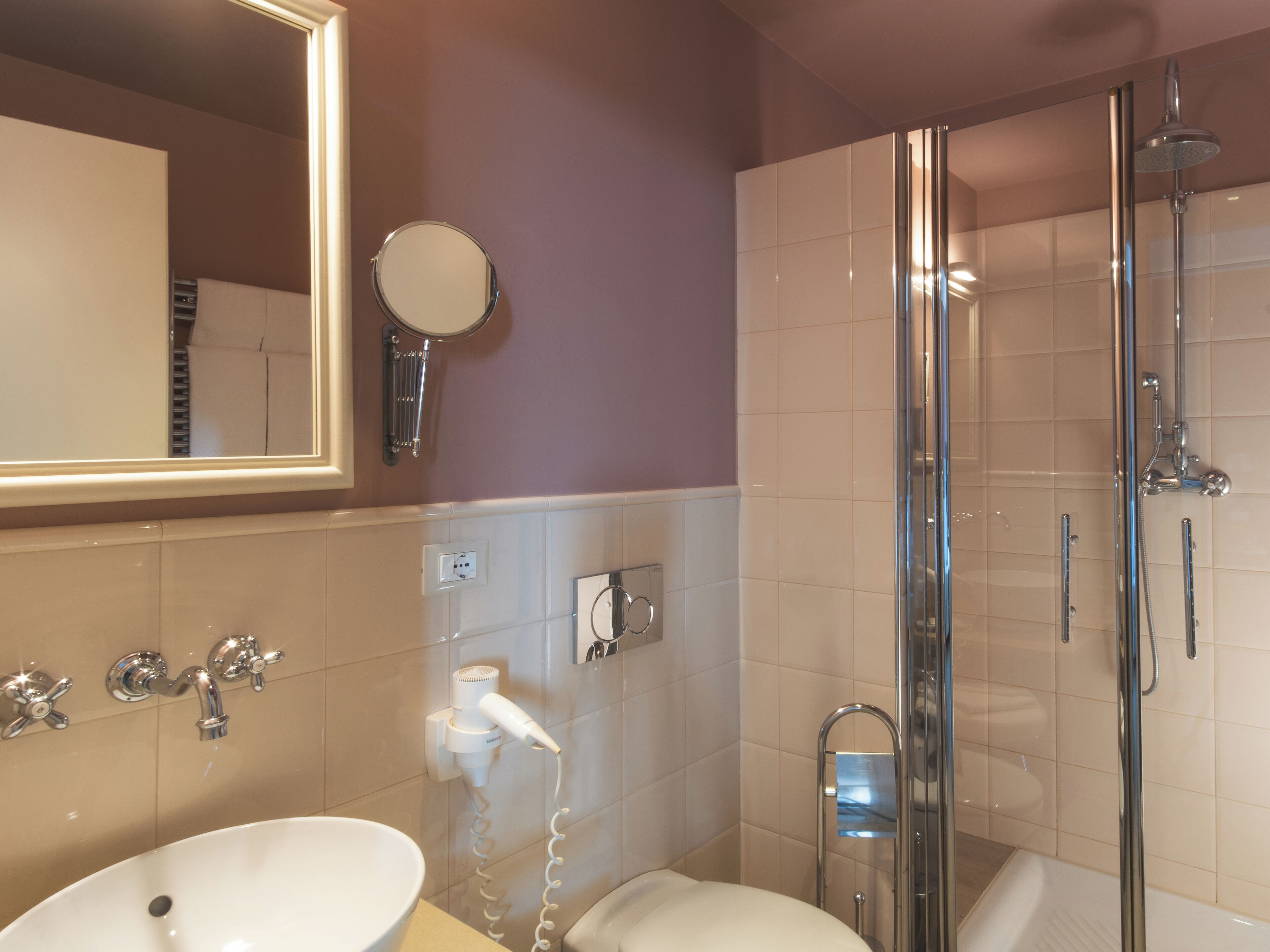 Un baño con lavabo, espejo, secador de pelo y ducha.
