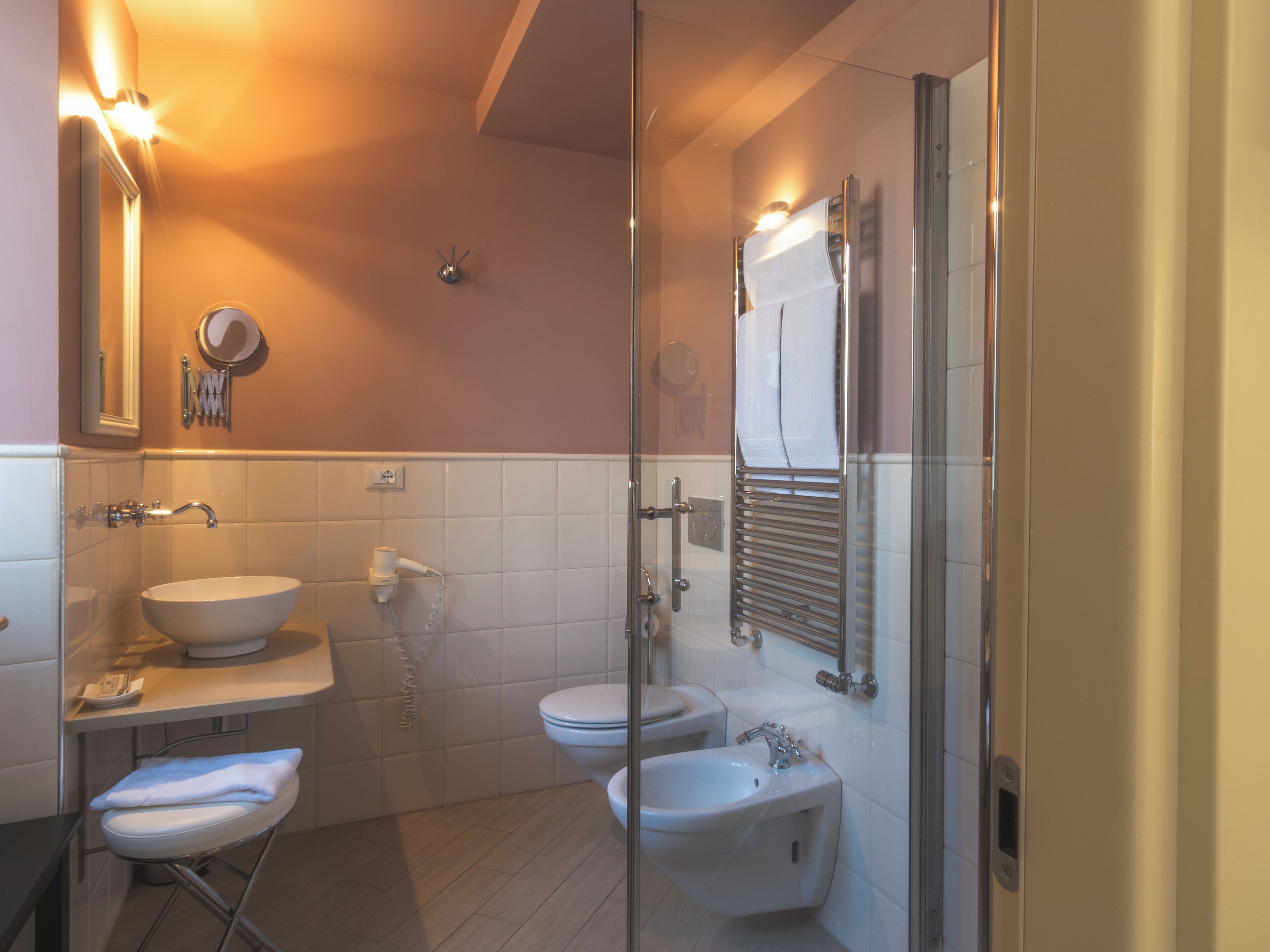 A modern bathroom with a sink, toilet, bidet, and glass shower enclosure.