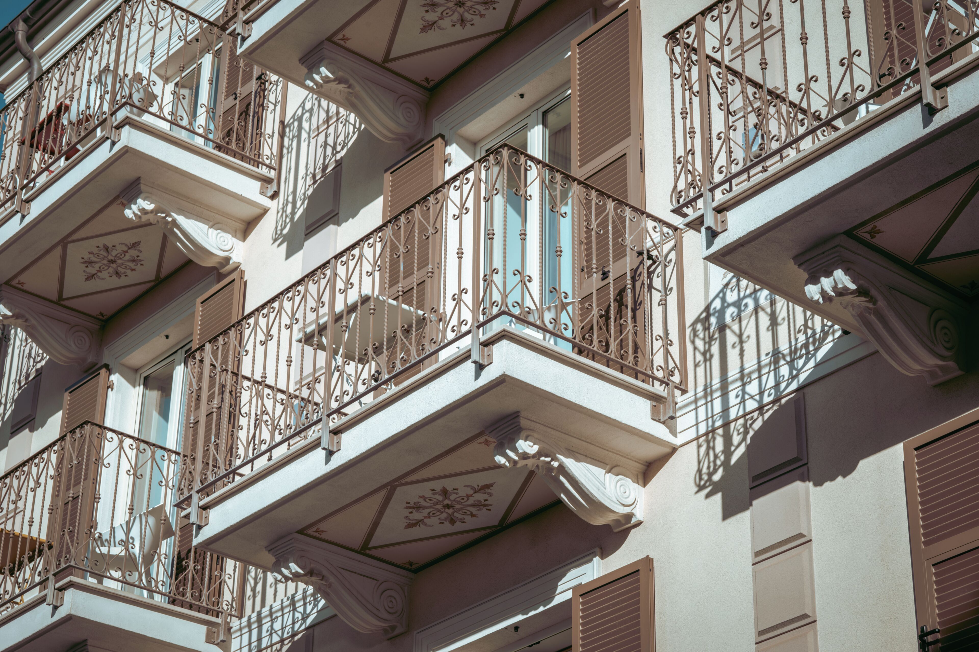 A building facade with multiple balconies featuring ornate wrought iron railings and decorative moldings.