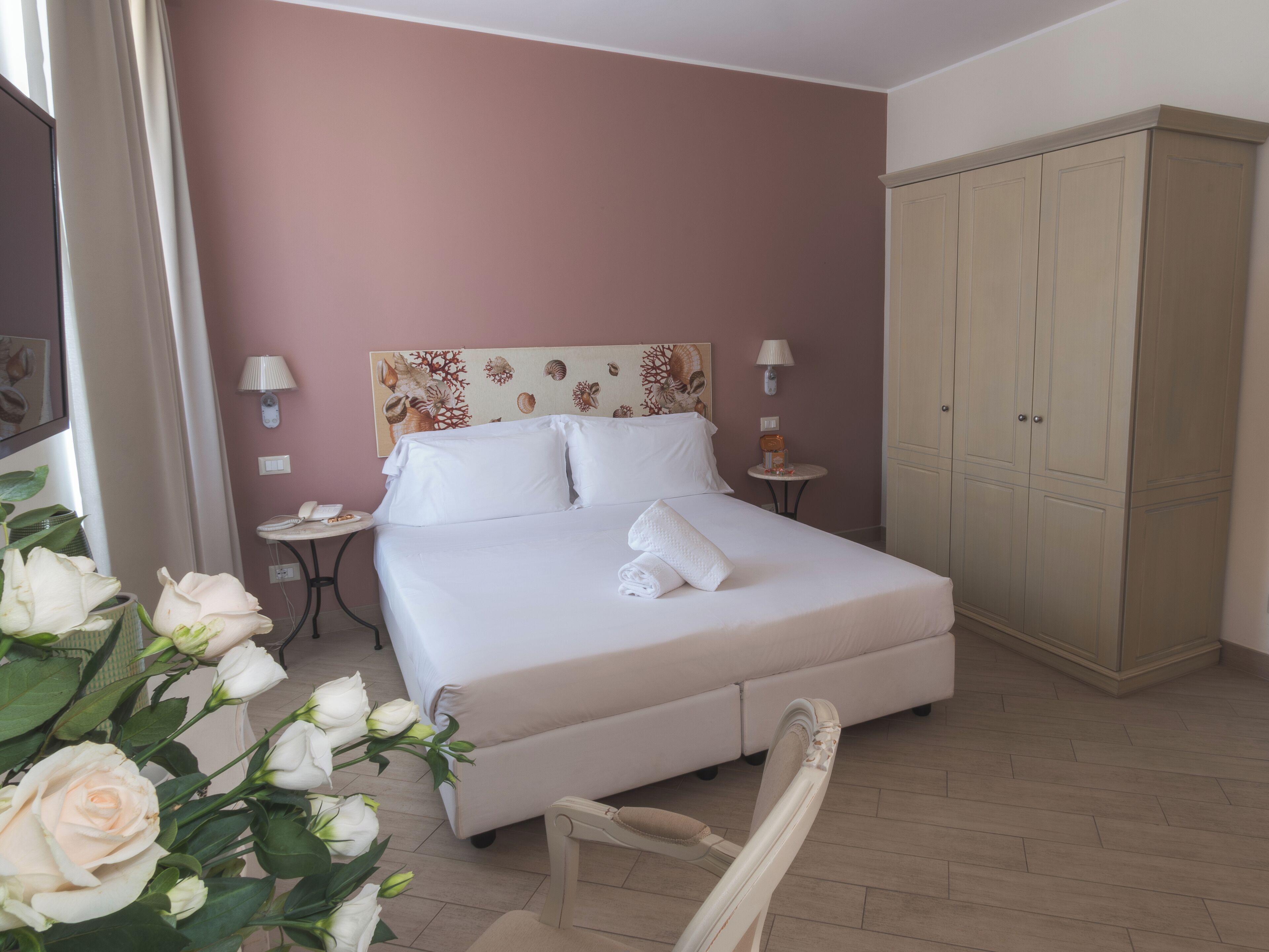 Une chambre à coucher comprenant un lit, des tables de chevet, une lampe, une armoire et une chaise.