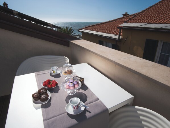A balcony with a table set for a meal, overlooking a coastal view. - San Pietro Palace Hotel (Finale Ligure)