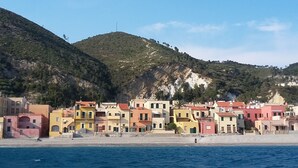 Eine Küstenstadt mit bunten Gebäuden, einem Strand und einer Bergkulisse.