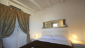 A hotel room with a bed, two bedside tables with lamps, a large mirror on the wall, and a window with curtains. - Gran Maestro B&B (Palermo)