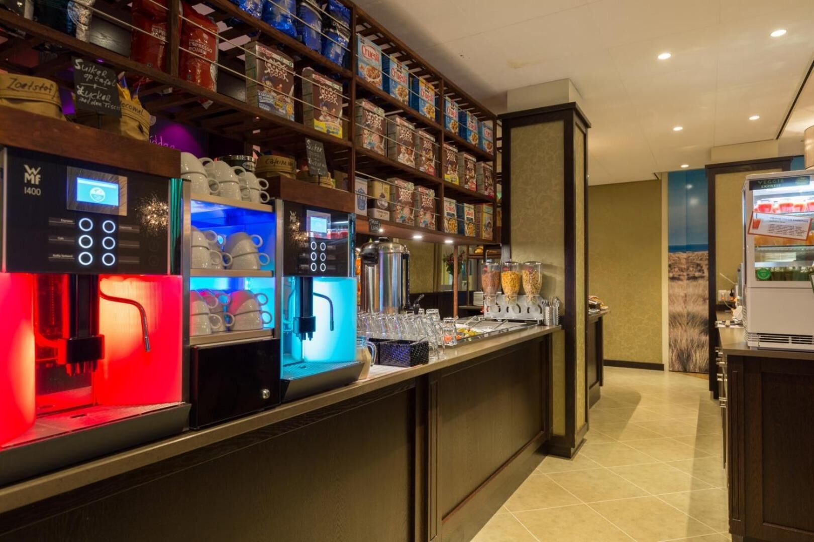 Una cafetería con varias máquinas de espresso y una variedad de cápsulas de café en estanterías.