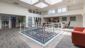 Un vaste atrium doté d’un sol en verre, de meubles modernes et d’un haut plafond agrémenté de lucarnes.