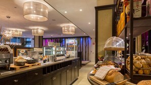Un comptoir de petit-déjeuner avec divers aliments, une machine à café et un présentoir à pain.