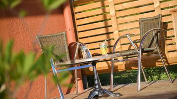 A wooden table with metal chairs, a glass with a straw, and a yellow cup on it.