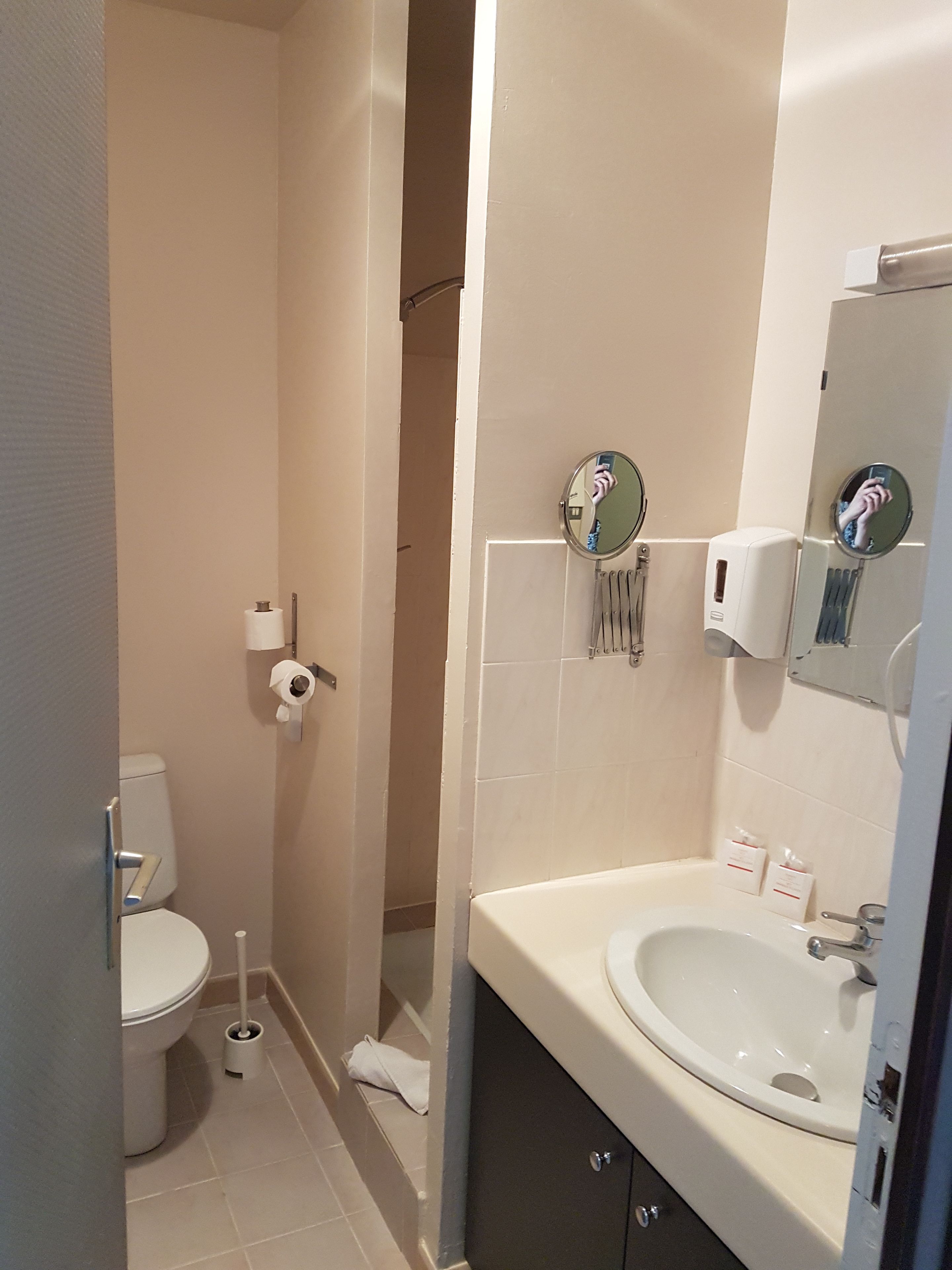 A bathroom with a toilet, a sink, a mirror, and a shower area.