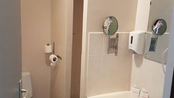 Un baño con inodoro, lavabo, espejo y zona de ducha.