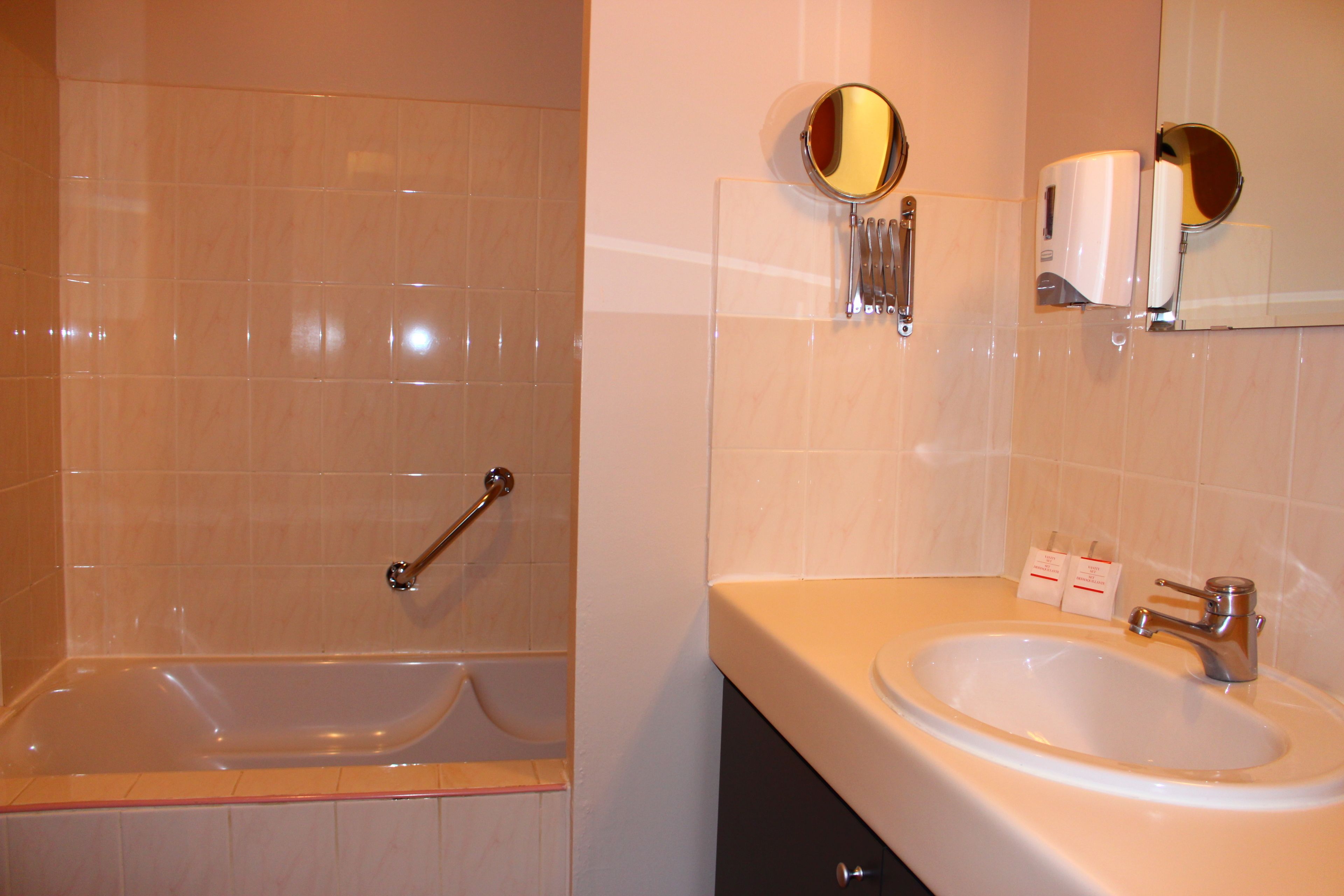 Une salle de bain avec une baignoire, un lavabo et un miroir.