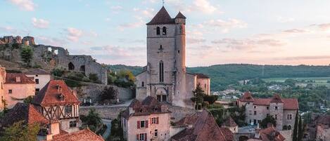 A historic town with a prominent tower, traditional half-timbered houses, and a castle in the background.