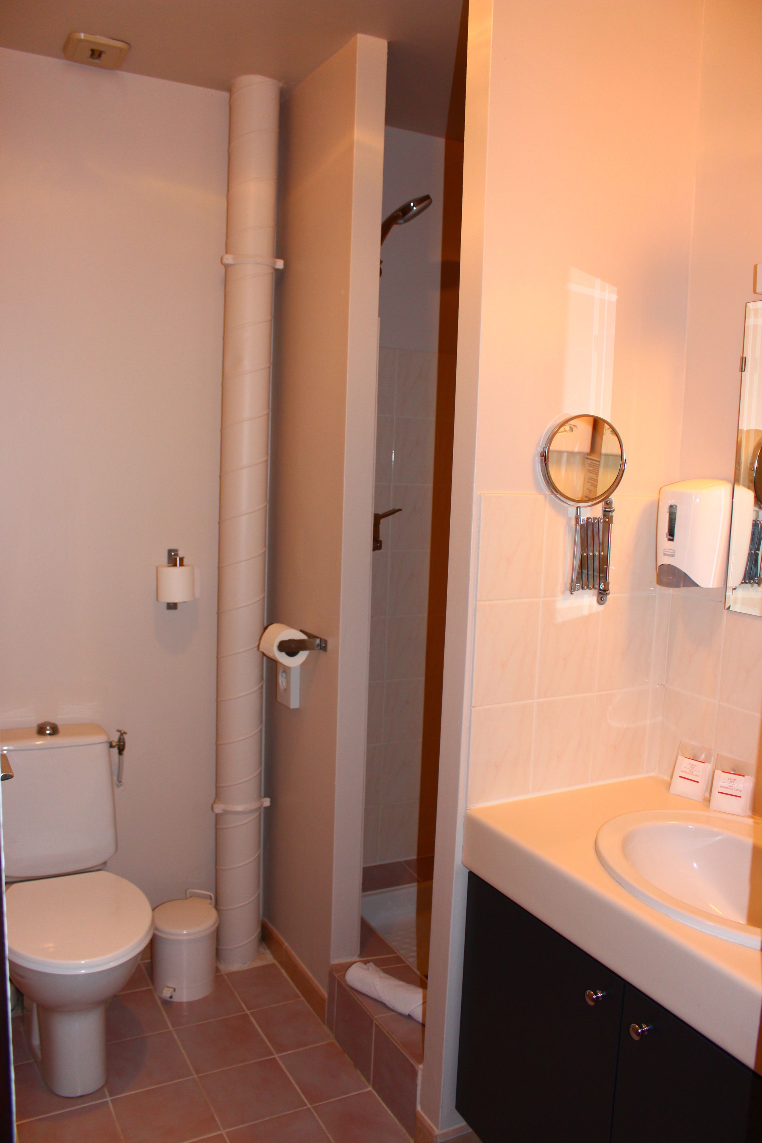 A bathroom with a toilet, sink, mirror, and towel rack.