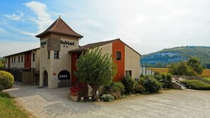 A hotel with a stone facade, a red roof, and a small tower.