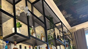 Una zona de bar con estantes llenos de botellas de licor, copas de vino y una máquina de café.
