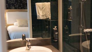 A bathroom with a sink, mirror, and shower.